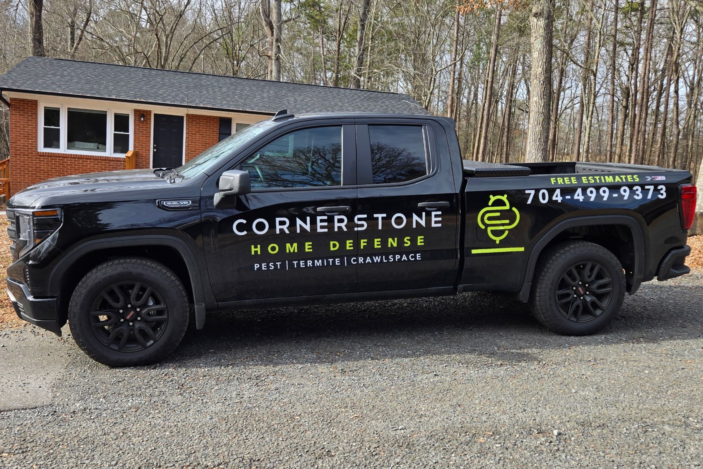kitchen-home-ant-defense-Fort-Mill-SC (1) Black GMC truck with Cornerstone Home Defense Pest Termite Crawlspace branding and phone number 704-499-9373 parked in gravel driveway.